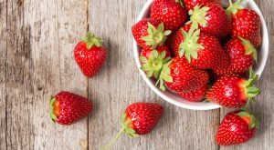 Red strawberry in a bowl on wooden background