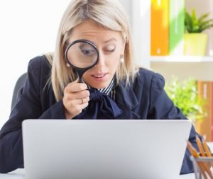 Woman looking at computer through a magnifying glass